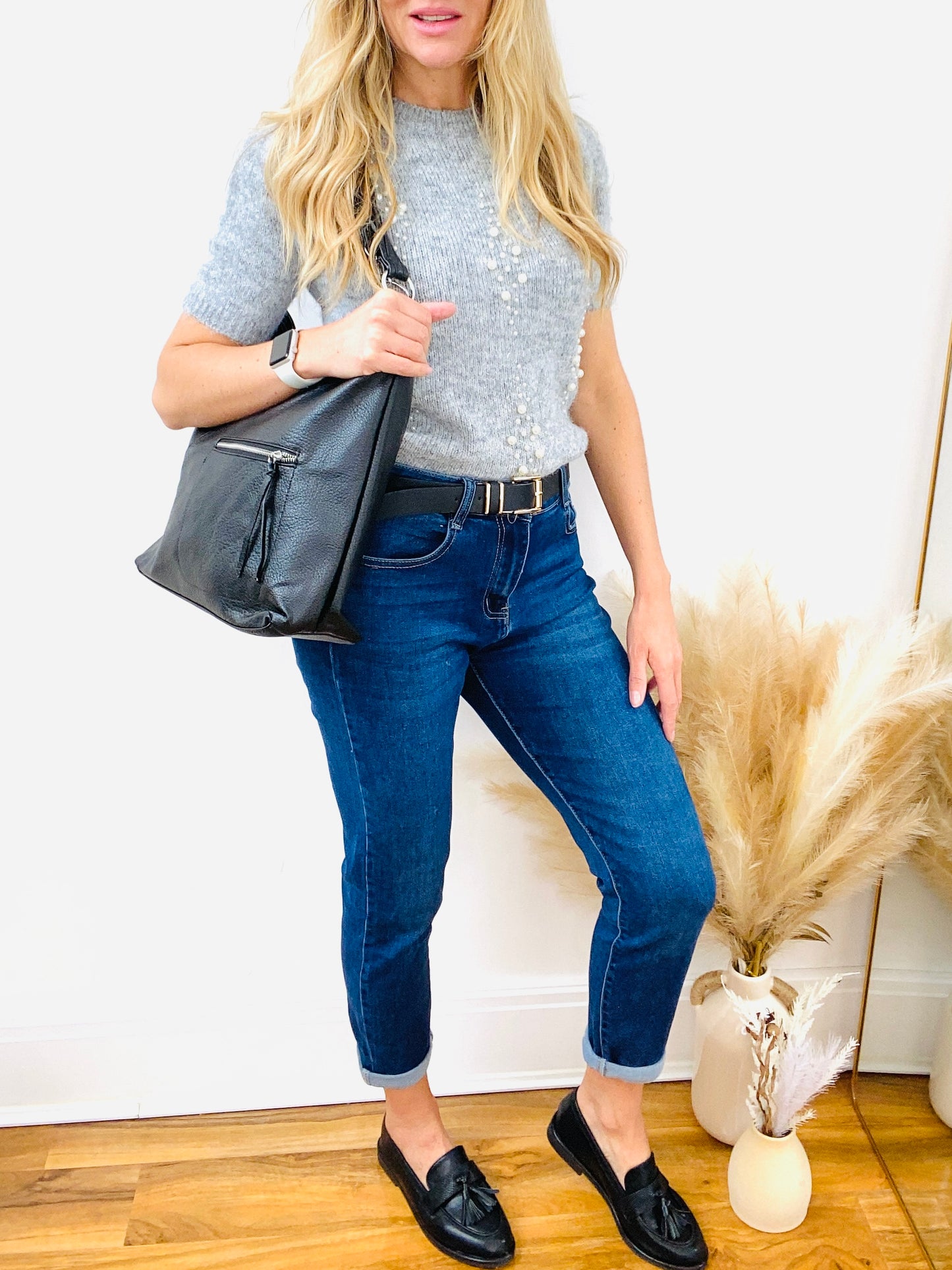 Grey short sleeve pearl jumper with dark denim mon fit jeans with black faux leather belt and faux leather loafer and slouch shoulder bag
