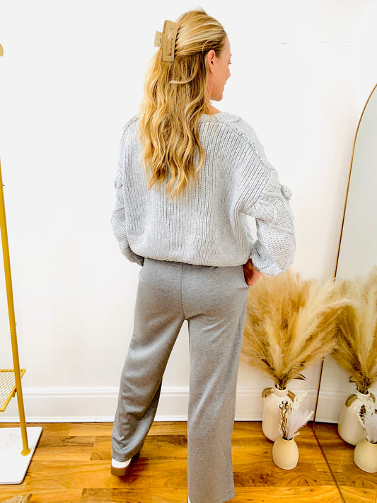 Back view of woman wearing a grey knitted cardigan and grey jogger pants