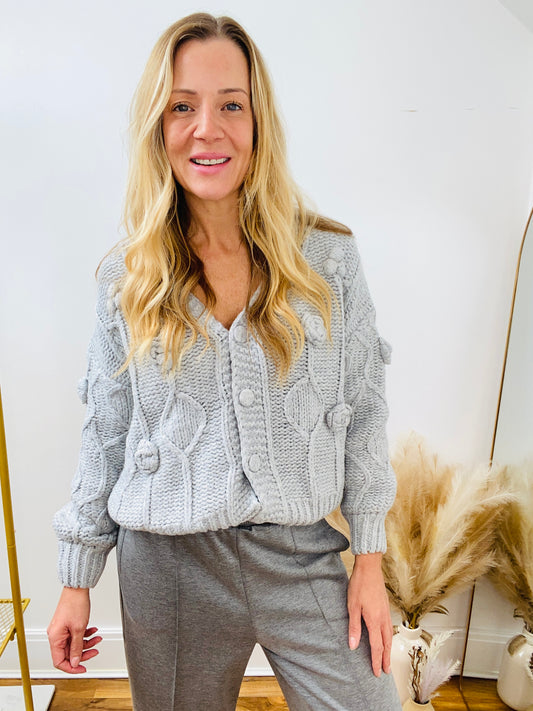 Woman wearing a grey knitted cardigan and grey jogger pants 