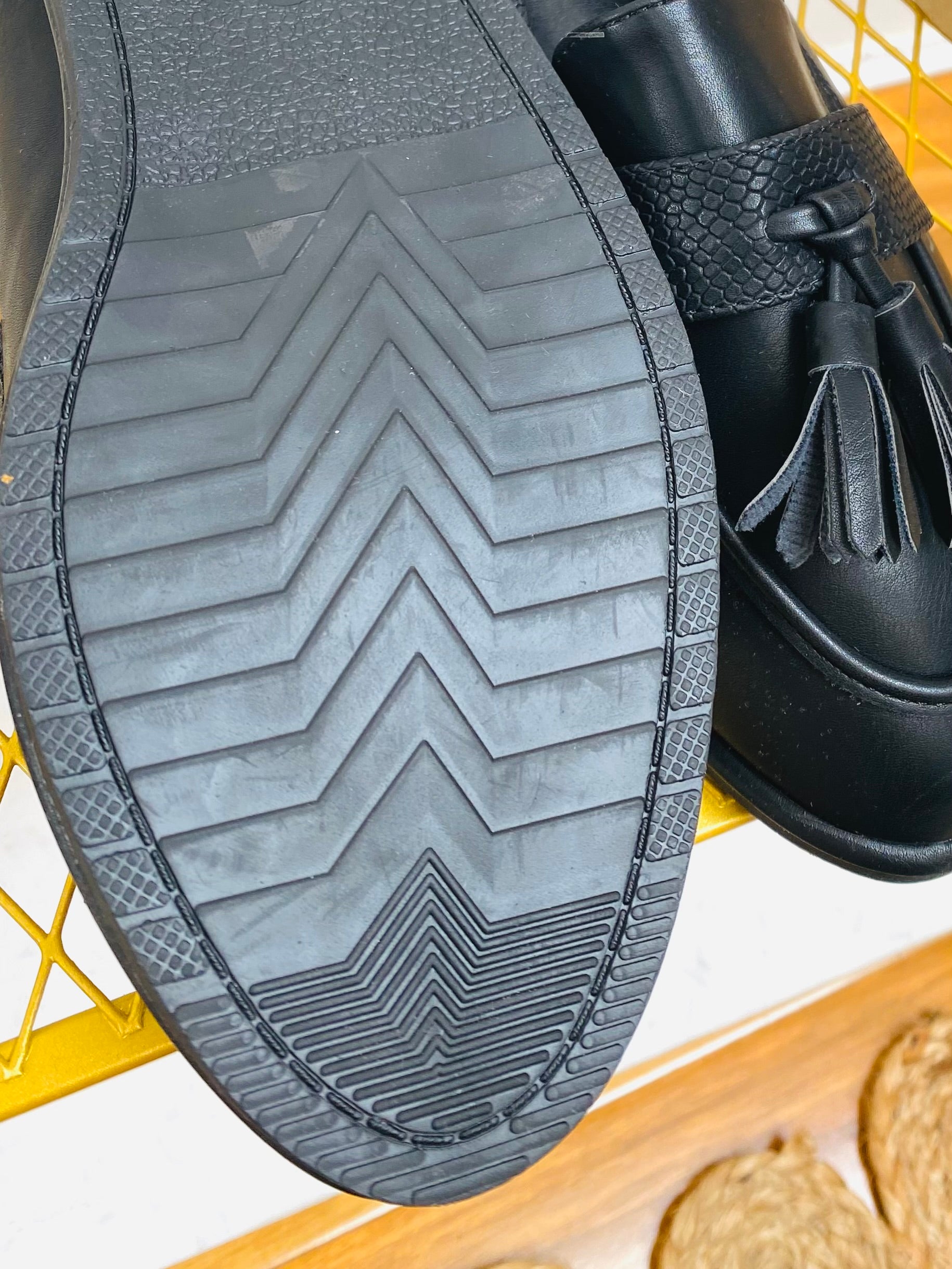 Black faux leather snake print tassel loafer, sole view.