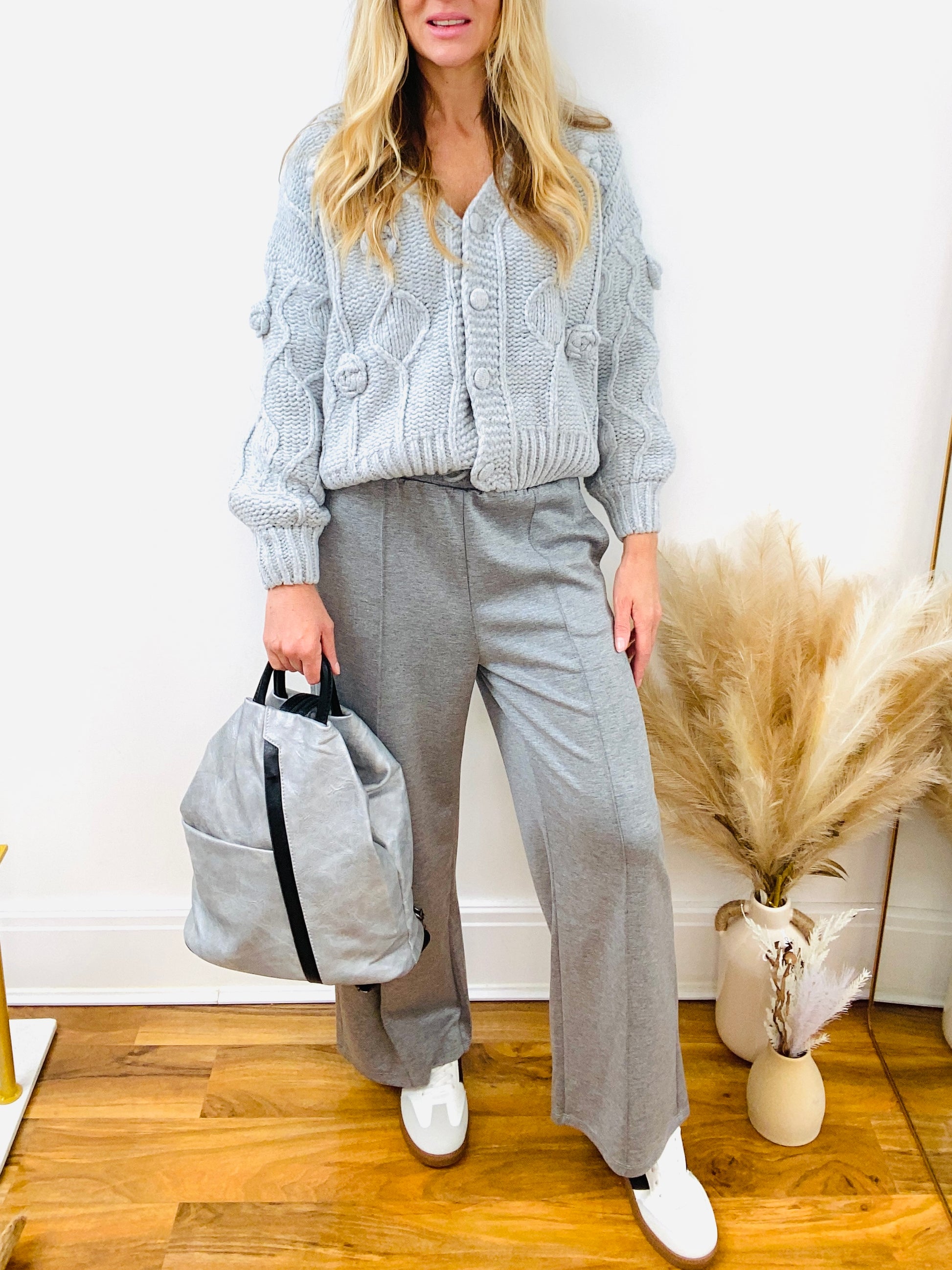 Top handle faux leather black and grey ruck sack with grey chunky cardigan and grey pin tuck joggers.